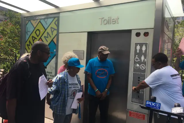 Monique George, executive director of Picture the Homeless, demonstrating that the public toilet at Madison Square Park does not work